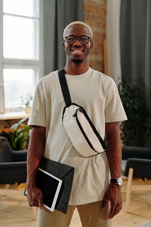 Un étudiant souriant avec ses lunettes et sa tablette sous le bras